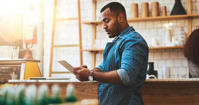 A business owner in his shop looking at a tablet.