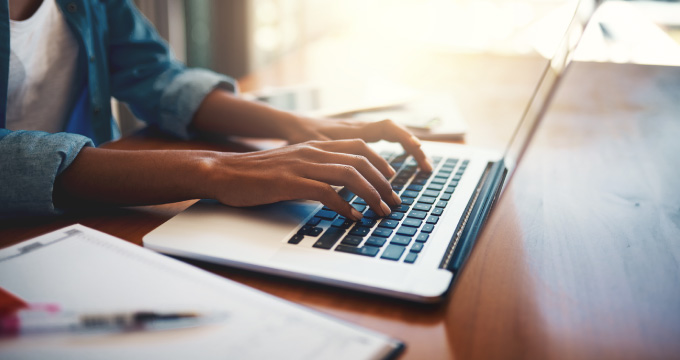 Close up of hands typing on a mac laptop.