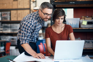 Two coworkers looking at a laptop.