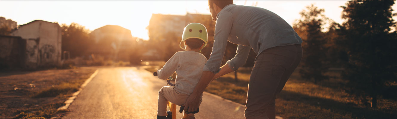 A father helping his son ride a bike for the first time.