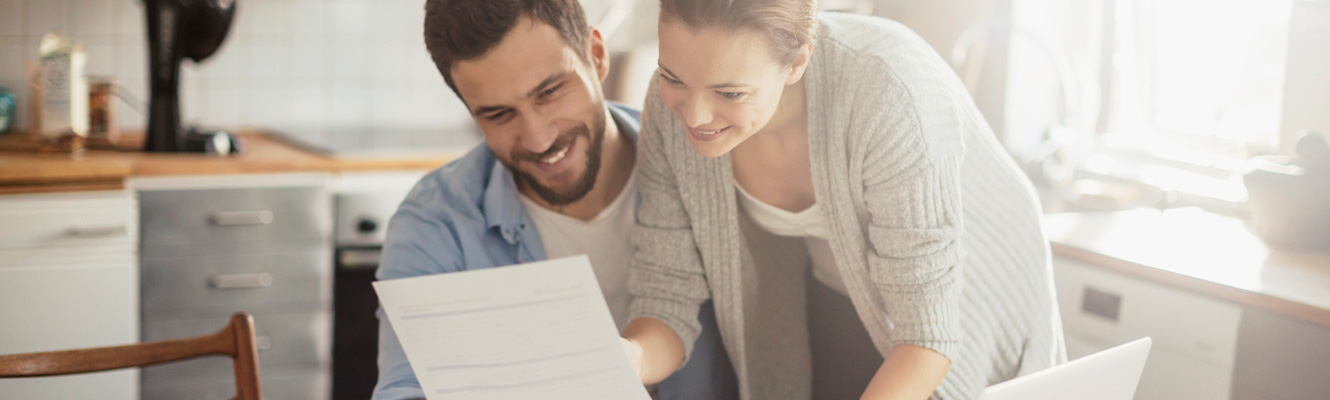 A couple in a kitchen looking at documents.