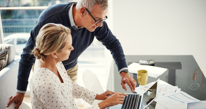 A middle-aged couple looking puzzled at a laptop screen. 