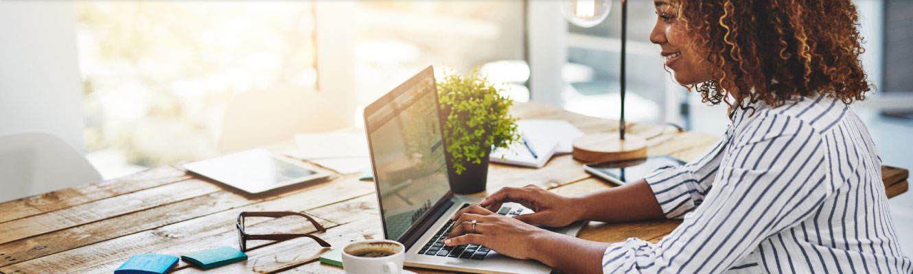 Woman sitting at a desk working on a laptop.